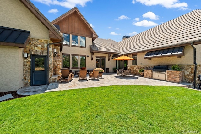 back of property with an outdoor kitchen, a patio area, and a yard