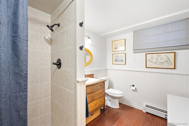 1100 Pontiac St, Denver, CO 80220 - bathroom featuring baseboard heating, wood finished floors, wainscoting, a tile shower, and vanity