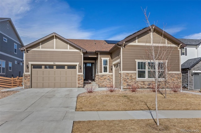 craftsman-style house with concrete driveway, stone siding, and an attached garage