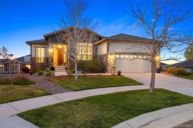 view of front of house featuring an attached garage, a yard, driveway, and stone siding