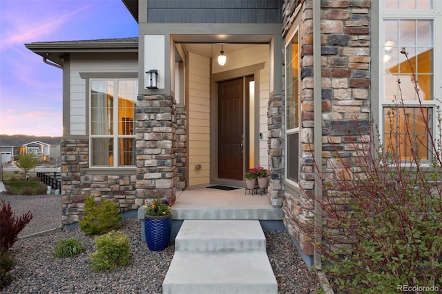 exterior entry at dusk featuring stone siding