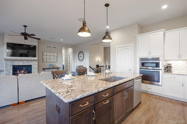 kitchen with light wood-style floors, ceiling fan, white cabinetry, a sink, and stainless steel appliances