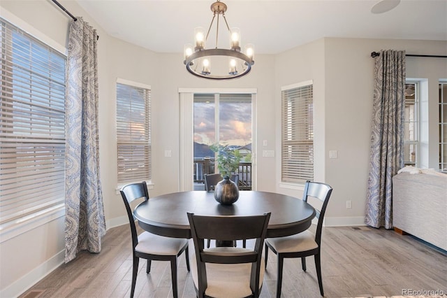 dining room with an inviting chandelier, light wood finished floors, and baseboards