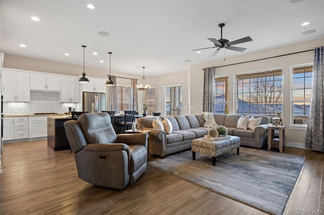 living area with recessed lighting, ceiling fan with notable chandelier, and wood finished floors