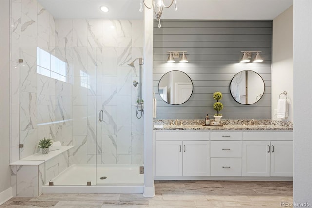 full bathroom with double vanity, a sink, a marble finish shower, and recessed lighting