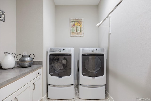 washroom featuring cabinet space, baseboards, and washing machine and dryer