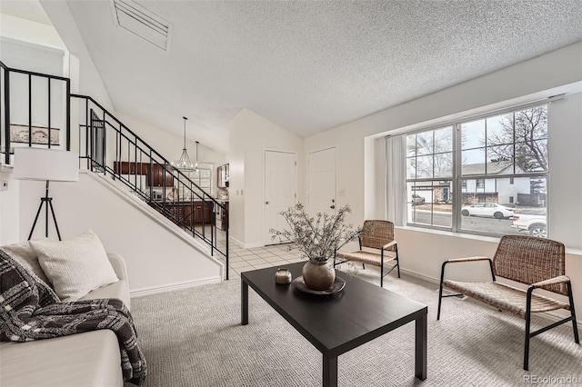 living area featuring a notable chandelier, lofted ceiling, light colored carpet, a textured ceiling, and stairs