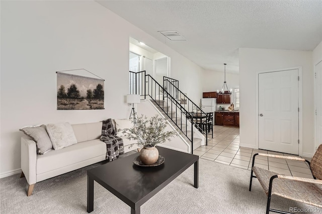 living area with light tile patterned floors, visible vents, stairway, vaulted ceiling, and a textured ceiling