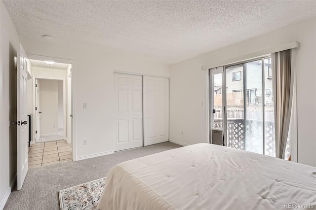 bedroom with access to exterior, a closet, carpet flooring, a textured ceiling, and baseboards