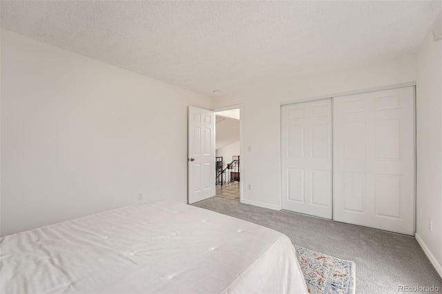 bedroom featuring light carpet, a closet, baseboards, and a textured ceiling