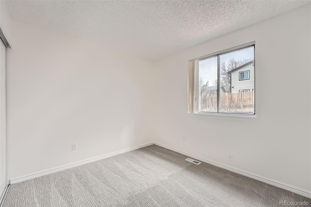 unfurnished room featuring baseboards, visible vents, a textured ceiling, and carpet flooring