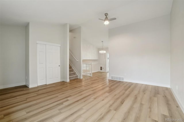 6337 W 68th Pl, Arvada, CO 80003 - unfurnished living room with light wood-style flooring, ceiling fan, baseboards, a chandelier, and stairs