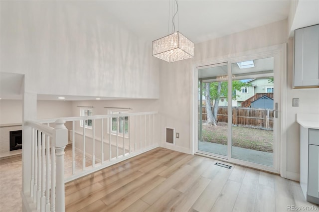 6337 W 68th Pl, Arvada, CO 80003 - unfurnished dining area featuring light wood-style floors, a fireplace with raised hearth, a chandelier, and baseboards