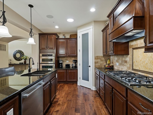 2363 Primo Rd Unit A, Highlands Ranch, CO 80129 - kitchen with custom range hood, stainless steel appliances, dark stone countertops, decorative light fixtures, and dark wood finished floors