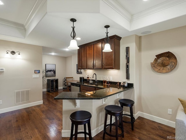2363 Primo Rd Unit A, Highlands Ranch, CO 80129 - kitchen featuring stainless steel dishwasher, a raised ceiling, a kitchen bar, ornamental molding, and dark wood-style flooring