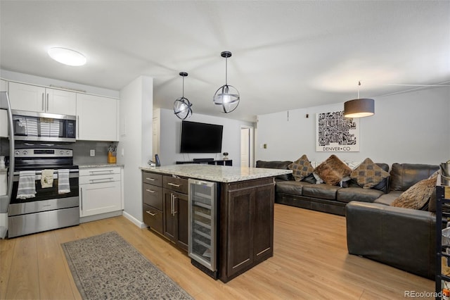 kitchen featuring beverage cooler, open floor plan, light wood-style flooring, and appliances with stainless steel finishes