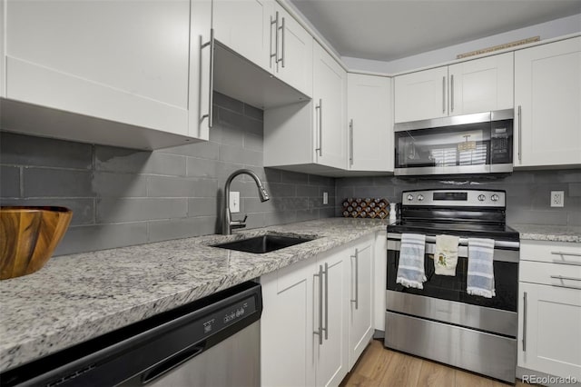 kitchen with a sink, white cabinetry, appliances with stainless steel finishes, and decorative backsplash