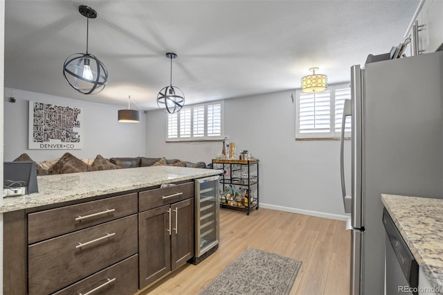 kitchen with wine cooler, dark brown cabinetry, open floor plan, light wood-style flooring, and stainless steel appliances