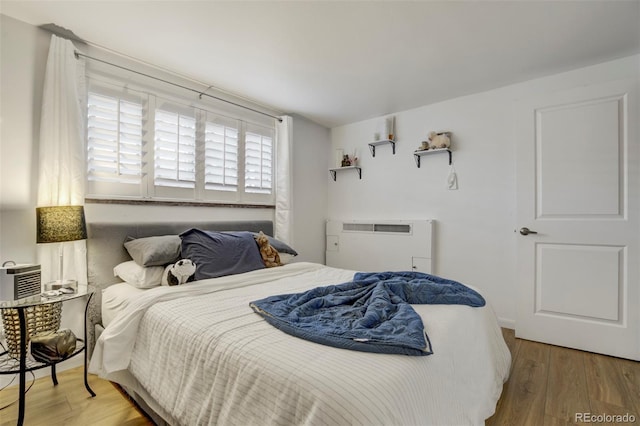 bedroom with an AC wall unit and wood finished floors