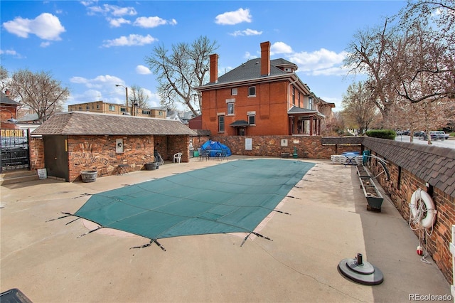 community pool featuring a patio, fence, and an outbuilding