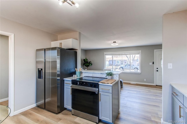 kitchen with gray cabinetry, white cabinetry, appliances with stainless steel finishes, and light wood-type flooring