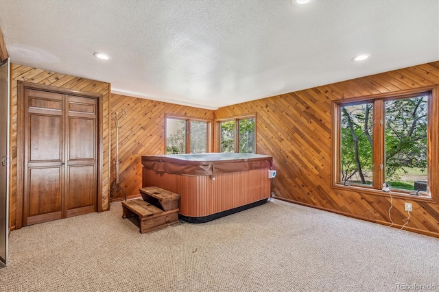 carpeted bedroom featuring multiple windows, wood walls, and a textured ceiling