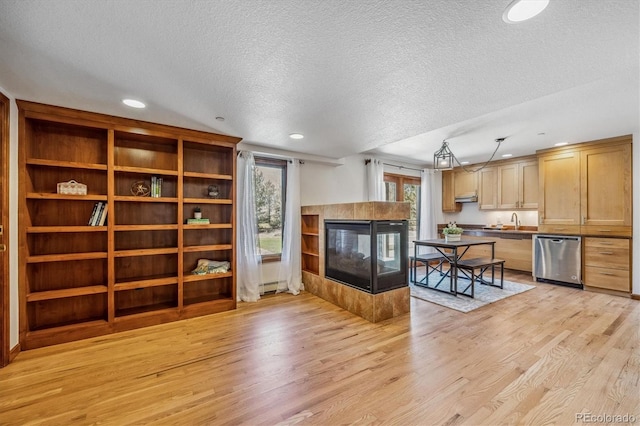 living room with plenty of natural light, light wood-type flooring, and a textured ceiling