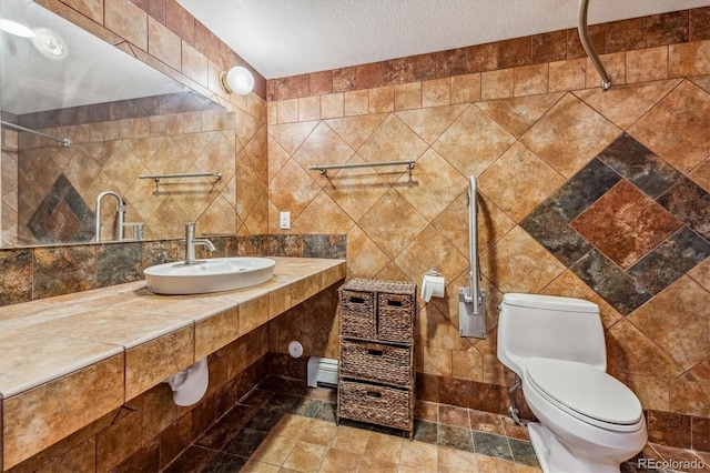 bathroom with a textured ceiling, sink, and tile walls