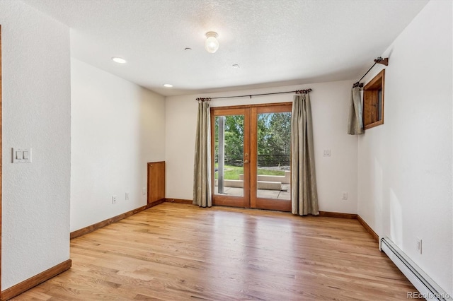 empty room with french doors, light wood-type flooring, a textured ceiling, and a baseboard heating unit