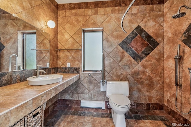 bathroom featuring sink, a healthy amount of sunlight, tile walls, and toilet