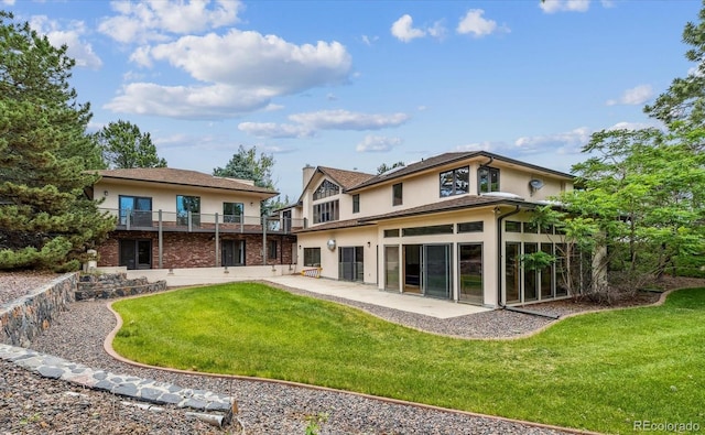 rear view of house featuring a yard, a sunroom, a balcony, and a patio