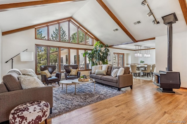 living room featuring hardwood / wood-style floors, high vaulted ceiling, a wood stove, and beam ceiling