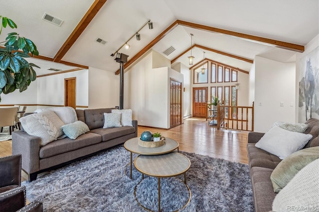 living room with wood-type flooring, a wood stove, rail lighting, and high vaulted ceiling