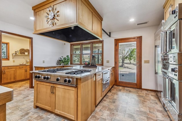 kitchen featuring premium range hood, light stone counters, and stainless steel gas cooktop