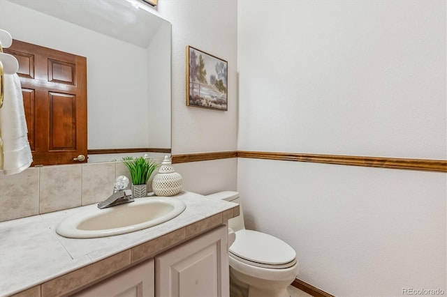 bathroom with vanity, tasteful backsplash, and toilet