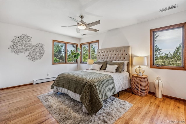 bedroom featuring hardwood / wood-style floors, baseboard heating, and ceiling fan