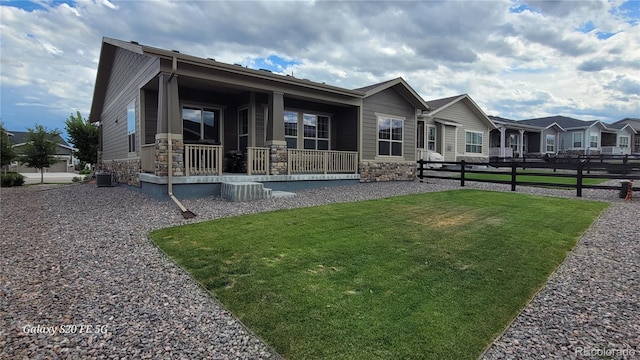 view of front of property with a porch, a front yard, and central AC