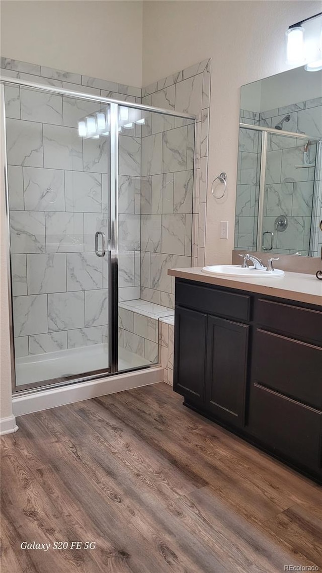 bathroom with hardwood / wood-style floors, vanity, and a shower with shower door