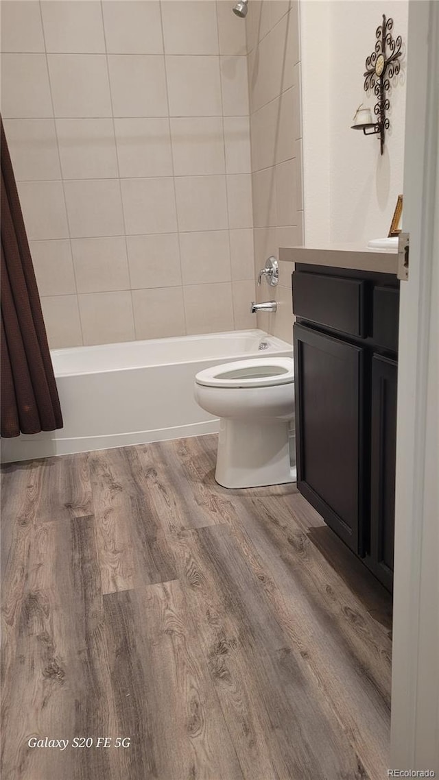 full bathroom with toilet, hardwood / wood-style floors, tiled shower / bath combo, and vanity