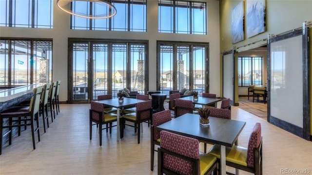 dining area with hardwood / wood-style flooring, plenty of natural light, and a high ceiling