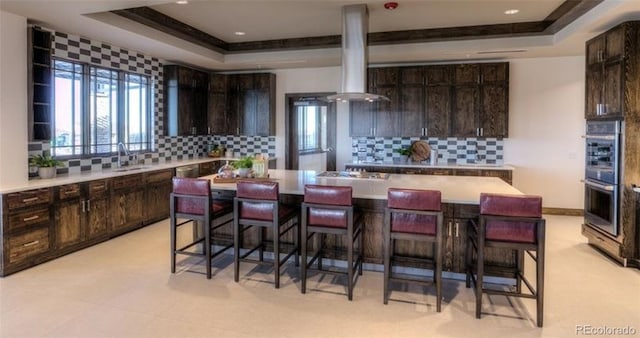 kitchen with light tile patterned floors, ventilation hood, tasteful backsplash, and dark brown cabinets