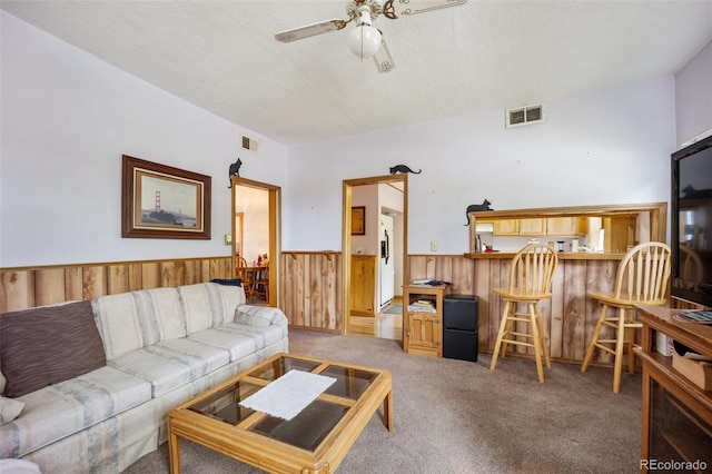 2402 W Uintah St, Colorado Springs, CO 80904 - living area featuring a ceiling fan, a wainscoted wall, wood walls, carpet, and a textured ceiling