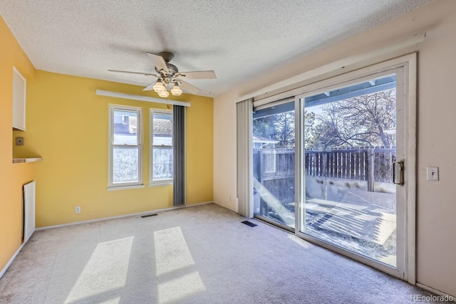 empty room featuring ceiling fan, light colored carpet, and a textured ceiling