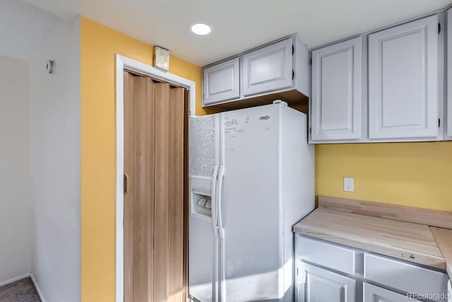 kitchen with white cabinetry and white fridge with ice dispenser