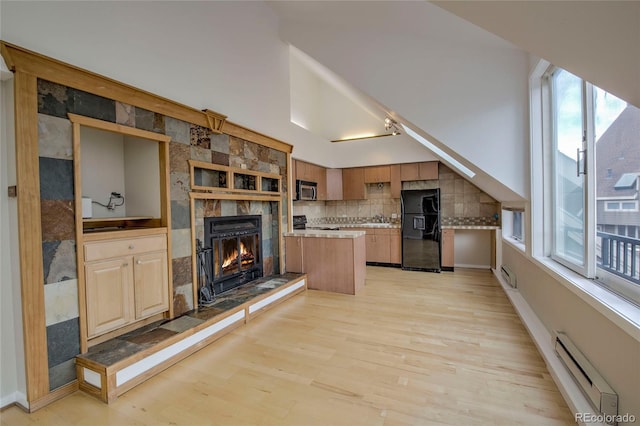 21650 US Highway 6 Unit 2096, Dillon, CO 80435 - kitchen with black fridge with ice dispenser, a baseboard heating unit, stainless steel microwave, light countertops, and a tile fireplace