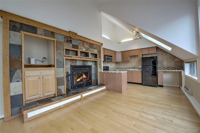 21650 US Highway 6 Unit 2096, Dillon, CO 80435 - kitchen with black fridge, stainless steel microwave, light wood-style floors, a fireplace, and light countertops