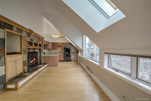21650 US Highway 6 Unit 2096, Dillon, CO 80435 - kitchen with freestanding refrigerator, a skylight, light wood-style floors, a tiled fireplace, and light countertops