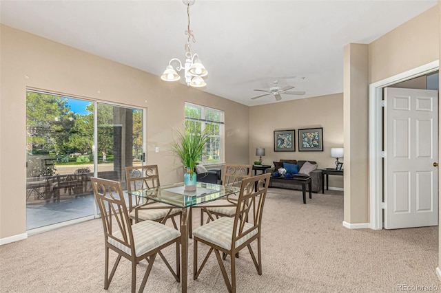 dining area featuring light carpet, ceiling fan with notable chandelier, and baseboards