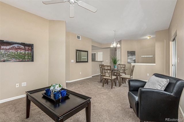 living room with visible vents, ceiling fan with notable chandelier, baseboards, and carpet