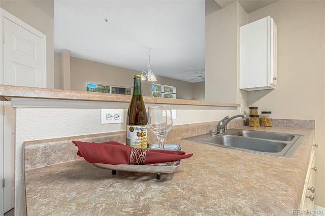 interior details with ceiling fan, decorative light fixtures, light countertops, white cabinets, and a sink